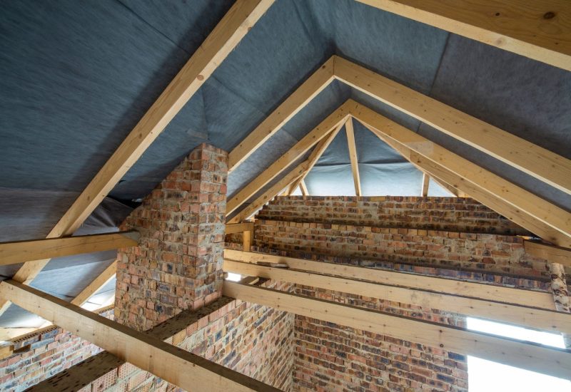 Converted loft space featuring original exposed stone wall and timber frame