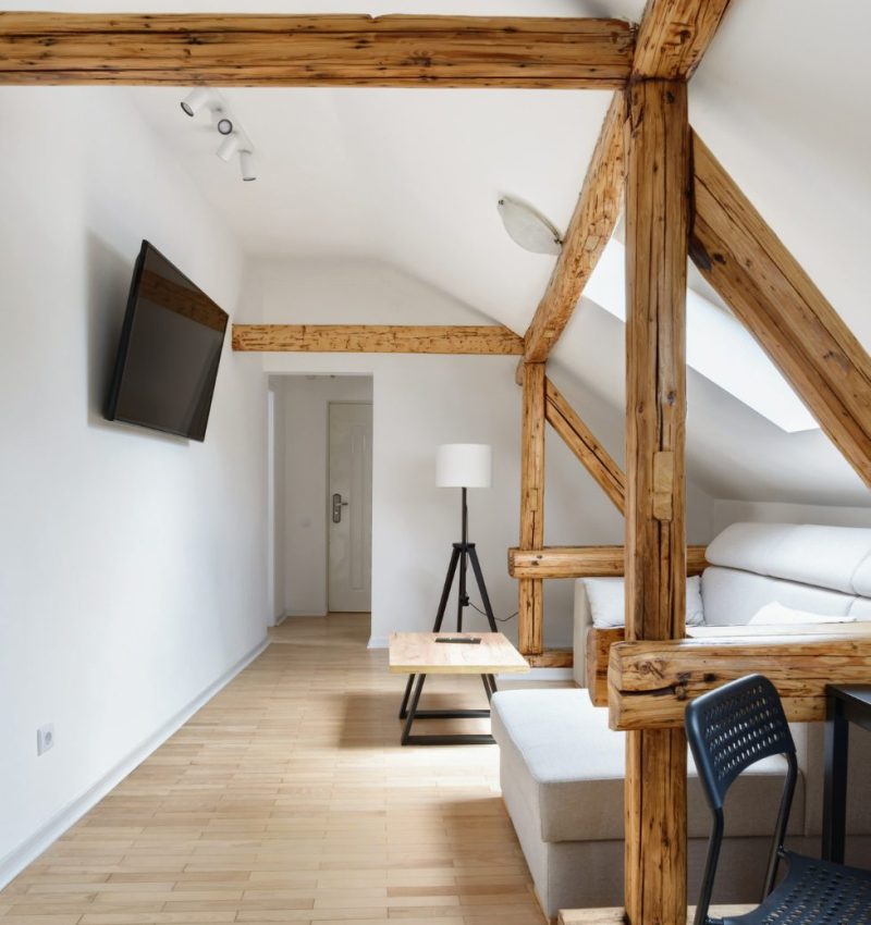 Open plan converted loft space with exposed beams and TV area